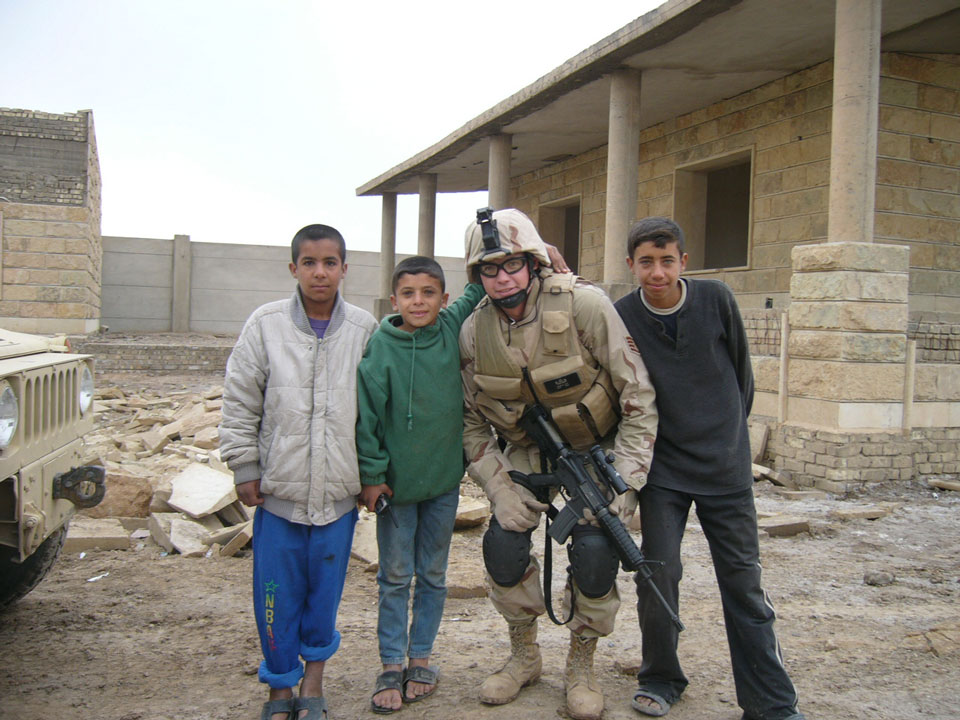 Adam with local Iraqi kids after removing explosive ordnance from near their house.